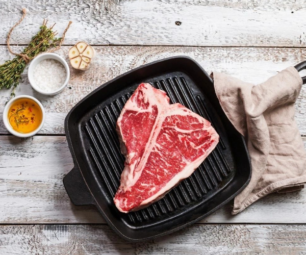 A steak is being cooked on the grill.